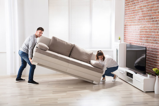 Couple Placing Sofa At Their New Home