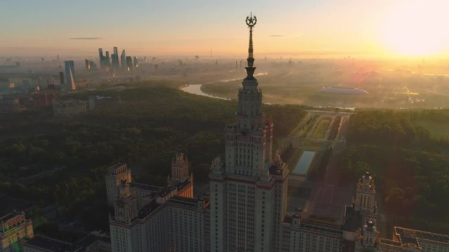 Flying over Moscow state university and Moscow city business center at sunny sunrise. City in fog. Russia. Aerial View.