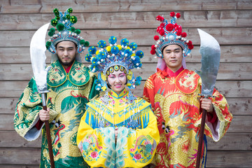Fototapeta na wymiar group of three asian people men and woman standing in a row and greeting outdoor in traditional chinese costumes