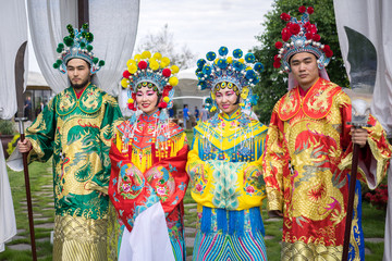 Naklejka premium group of four asian people men and women standing in a row and greeting outdoor in traditional chinese costumes