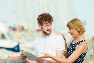 Tourist couple in marina looking up directions on map