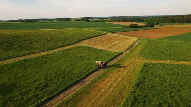 Traktor mit Feldern und Wiesen bei Sonnenuntergang in Süddeutschland