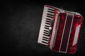 Red accordion on wooden grey background. Write text