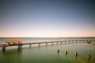 Fototapeta na wymiar Long exposure of a long walkway over the water with pier