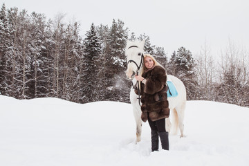 Nice girl and white horse outdoor in a winter