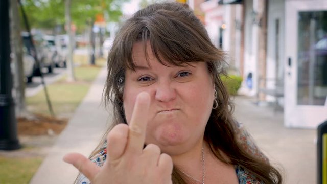 Very angry woman gives the middle finger to the camera