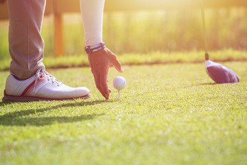 A man playing golf in green course. Focus on golf ball.