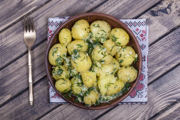 Boiled potatoes with dill, garlic and butter in a plate on wooden table
