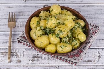 Boiled potatoes with dill, garlic and butter in a plate on wooden table