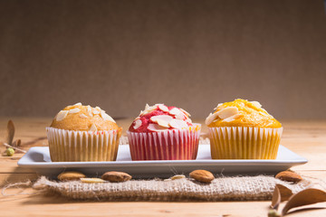 Sweet muffins with almond on  wooden table.