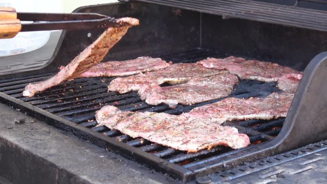 Man's hands cooking meat on grill