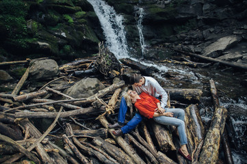 Obraz premium loving couple near a waterfall in forest.