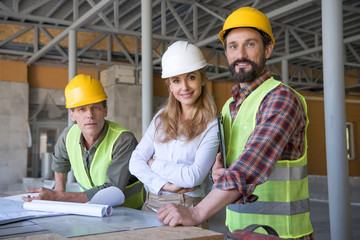 middle aged constructors and contractor looking at camera during work on construction site