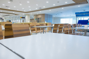 Interior of white table and wooden table on food court in shopping mall.