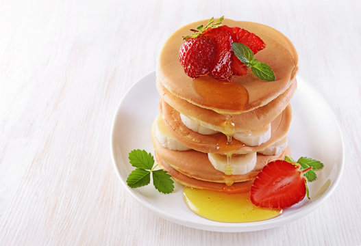 Tasty breakfast. Homemade pancakes with fresh strawberry and banana, honey and mint