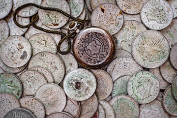 Fototapeta na wymiar Back cover pocket watch on a bunch of old silver coins.