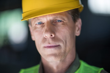 Close-up portrait of middle aged builder in hard hat looking at camera