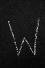 Letter W drawn with white chalk on blackboard. Education, school concept