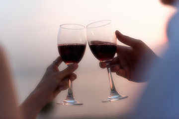 Close-up of couple hands holding champagne flutes during celebration at sunset beach.