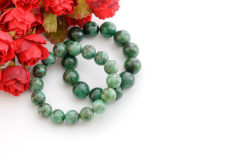 Beautiful valuable Emerald stone beads in bracelet with red roses on white background