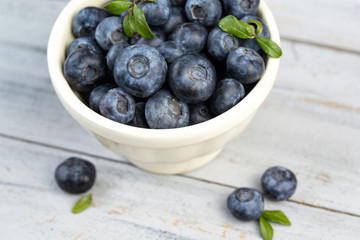 Bowl with fresh blueberries on wooden background