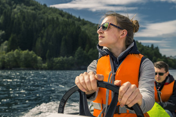 Portrait of young and attractive woman close up driving the motorboat, Norway. She is enjoying the...