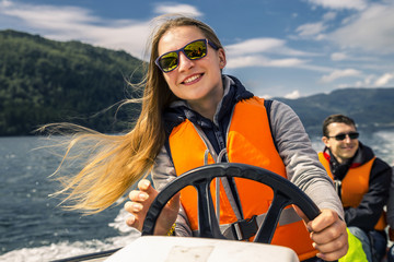 Portrait of young and attractive woman close up driving the motorboat, Norway. Beautiful, ruffled hair. - obrazy, fototapety, plakaty