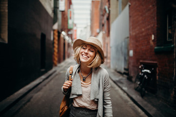 Urban life portrait of smiling woman in the middle of a narrow street.