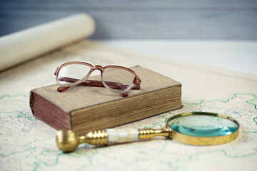 Old glasses and golden magnify glass on ancient book and old map