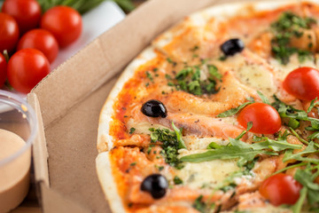 italian pizza with salmon, tomatoes, arugula and cheese