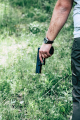 The gun is in his hand. The man is ready to shoot at the target