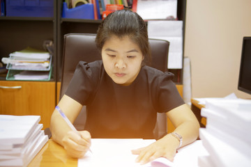 Naklejka premium Asian businesswoman is writing a paper on a desk in office room as selective focus