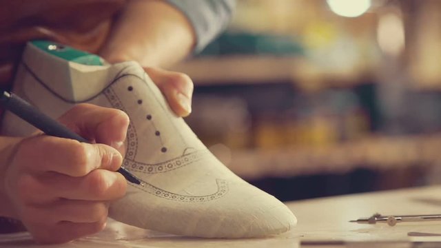 Cropped video of young shoemaker sitting in workshop making shoes