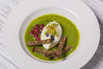 Cooking with local ingredients - poached egg and green healtfy soup, close up