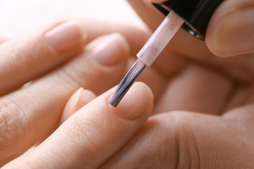 Master applying nail polish on woman fingernails