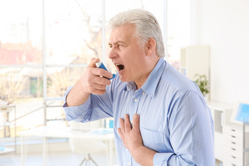 Fototapeta premium Elderly man using inhaler in clinic