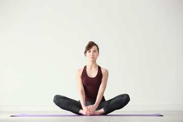 Young woman practicing yoga on light background indoors