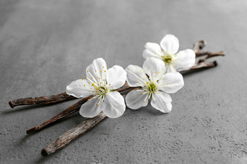 Dried vanilla sticks and flowers on grey textured background, closeup