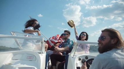 Group of laughing friends having fun on boat and taking selfie.