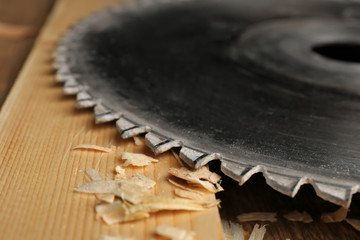 Circular-saw disk and wooden board in carpenter's workshop, closeup