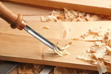Working with chisel and wooden board in carpenter's shop, closeup