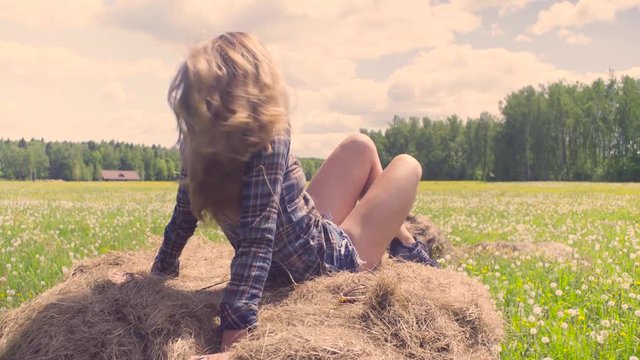 Young woman laying on haystack at summer