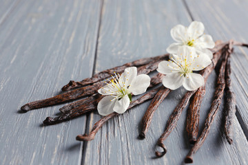 Dried vanilla sticks and flowers on wooden background, closeup
