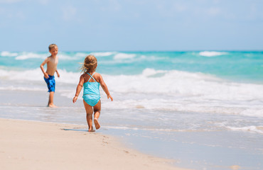 Naklejka premium little girl and boy run play with waves on beach