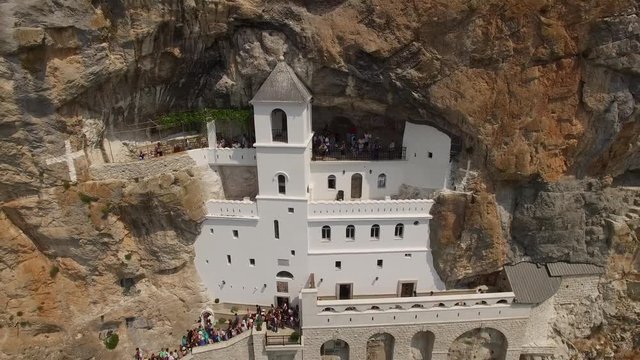 Unique old historical Ostrog white Monastery in the rock central Montenegro. Famous tourist religion Orthodox Church. Aerial drone flight around. Summer day