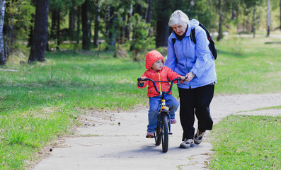 Fototapeta premium Grandmother teaching little granddaughter to ride bike