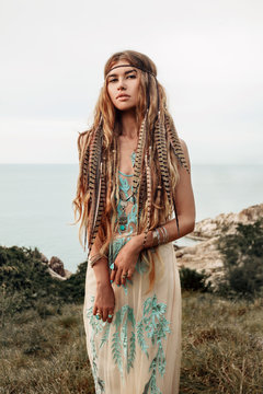 beautiful young boho girl on a hill with sea background