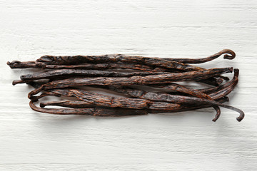 Dried vanilla sticks on light wooden background, closeup