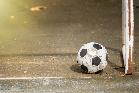 Old soccer ball on the cement floor.