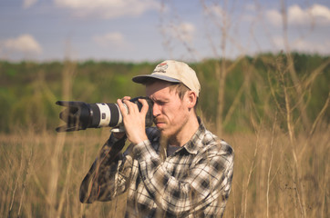 A hipster photographer takes photos in the countryside